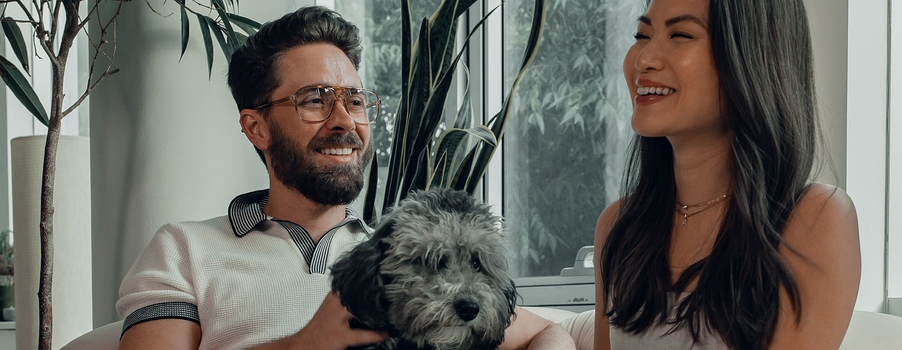 lifestyle image of a couple indoors smiling beside their pet